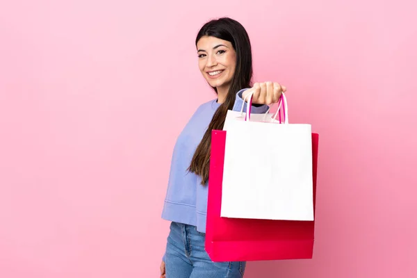Jong Brunette Meisje Geïsoleerde Roze Achtergrond Holding Boodschappentassen Geven Aan — Stockfoto