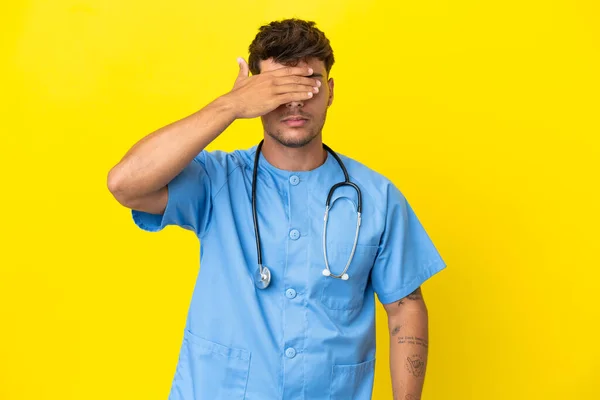 Jovem Cirurgião Homem Médico Isolado Fundo Amarelo Cobrindo Olhos Por — Fotografia de Stock
