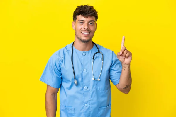 Jovem Cirurgião Homem Médico Isolado Fundo Amarelo Mostrando Levantando Dedo — Fotografia de Stock