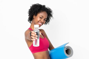 Beyaz arka planda izole edilmiş genç Afrikalı Amerikalı bir kadın spor su şişesi ve bir paspas ile