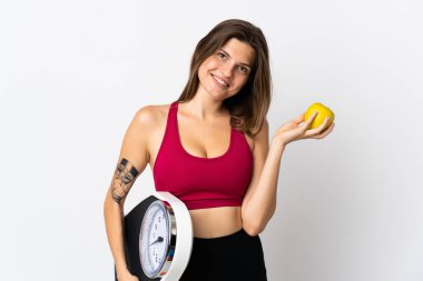 Genç Slovak kadın beyaz arka planda tartı makinesi ve elmayla izole edilmiş.