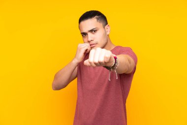 Asyalı yakışıklı adam sarı arka planda izole edilmiş, şaşırmış ve bir mesaj gönderiyor.