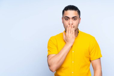 Asyalı yakışıklı adam izole edilmiş arka planda ağzını eliyle kapatıyor.