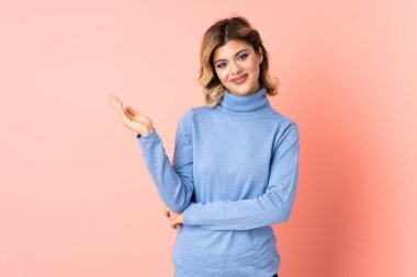 Pembe arka planda izole edilmiş genç bir Rus kadını davet etmek için ellerini yana uzatıyor.
