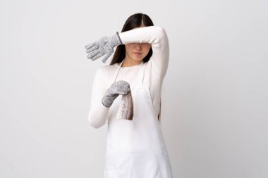 Çinli balıkçı önlük takıyor ve çiğ bir balığı izole edilmiş beyaz arka planda tutuyor. Gözleri elle kaplıyor.