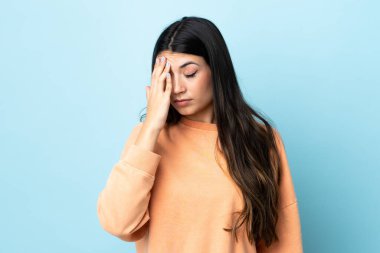 Genç esmer kız soyutlanmış mavi arka planda baş ağrısı var.