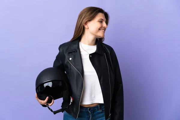 若いですSlovak女性保持Aオートバイヘルメット隔離上の紫の背景探している側 — ストック写真