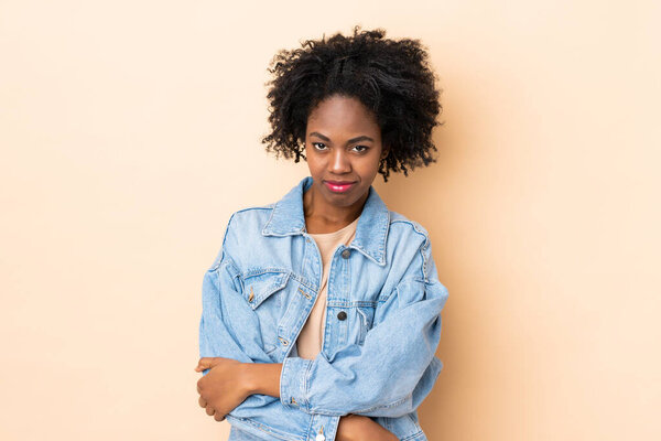 Young African American woman isolated on beige background with sad expression