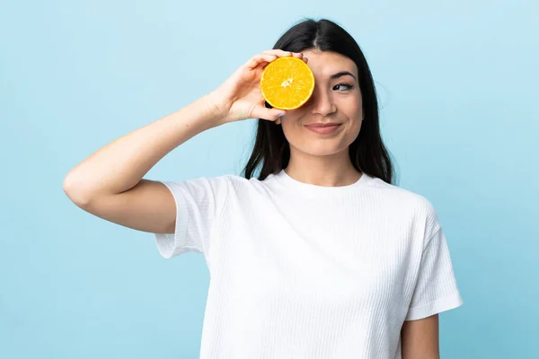 Ung Brunett Flicka Över Isolerad Blå Bakgrund Håller Orange — Stockfoto