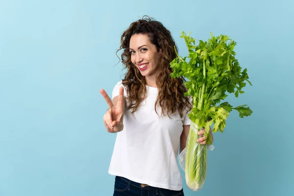 Young Woman Holding Celery Isolated Blue Background Smiling Showing Victory — Stock Photo, Image