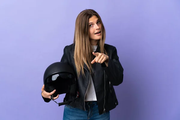 若いですSlovak女性を保持していますオートバイヘルメット隔離上の紫の背景驚きと指摘フロント — ストック写真