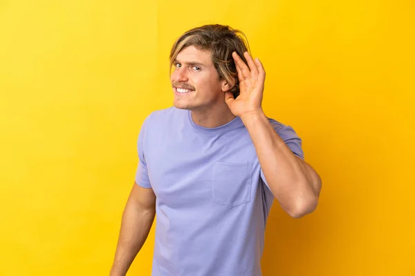 Knappe Blonde Man Geïsoleerd Gele Achtergrond Luisteren Naar Iets Door — Stockfoto