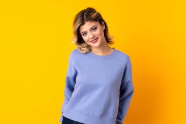 Sarı arka planda yalnız yaşayan genç Rus kadın gülüyor.