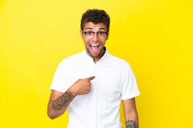 Sarı arka planda yalıtılmış yakışıklı Brezilyalı bir adam. Şaşırtıcı bir yüz ifadesi var.