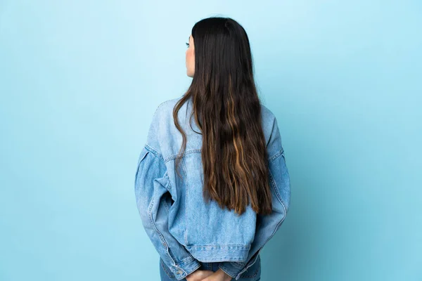 Jovem Morena Sobre Fundo Azul Isolado Posição Traseira Olhando Para — Fotografia de Stock