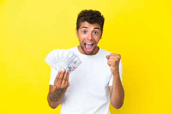 Joven Brasileño Tomando Mucho Dinero Aislado Sobre Fondo Amarillo Celebrando — Foto de Stock