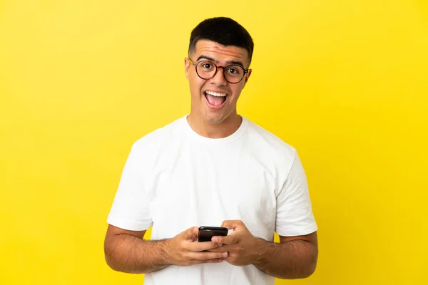 Joven Hombre Guapo Sobre Fondo Amarillo Aislado Sorprendido Enviando Mensaje — Foto de Stock