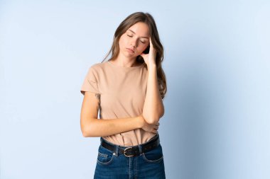 Genç Litvanyalı kadın mavi arka planda başağrısı ile izole edilmiş.