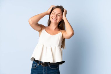 Genç Litvanyalı kadın mavi arka planda izole edilmiş gülüyor.