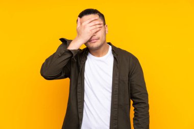 Asyalı yakışıklı adam sarı arka planda izole edilmiş, çok gülümsüyor.