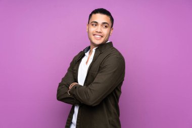 Asyalı yakışıklı adam mavi arka planda izole edilmiş kolları bağlı ve mutlu.