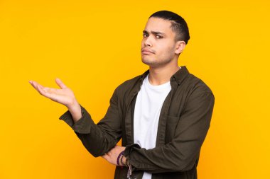 Asyalı yakışıklı adam sarı arka planda tek başına zaferi kutluyor.