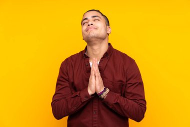 Asyalı yakışıklı adam sarı arka planda izole edilmiş. Şüpheleri var ve kafası karışmış bir yüz ifadesi var.