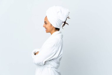 Bornozlu genç bir kadın, soyutlanmış beyaz arka planda, yan pozisyonda.