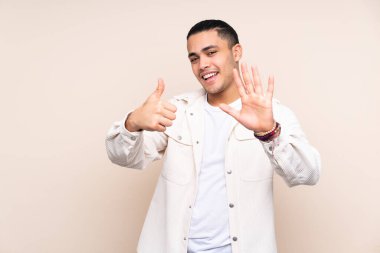 Asyalı yakışıklı adam izole edilmiş arka planda altı parmaklı sayıyor.