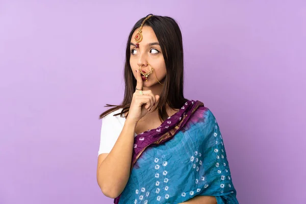 紫色の背景に孤立した若いインド人女性が口の中に指を入れて沈黙のジェスチャーの兆候を示す — ストック写真