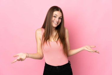 Pembe arka planda izole edilmiş genç beyaz kadın mutlu ve gülümsüyor.