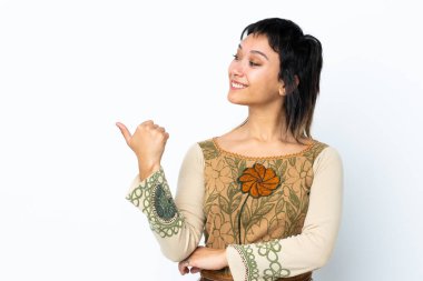 İzole edilmiş beyaz arka planda genç Uruguaylı kız bir ürünü sunmak için kenarı işaret ediyor.