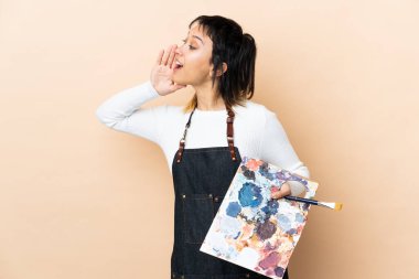 Arkaplanda palet tutan genç bir sanatçı ağzı açık bağırıyor.