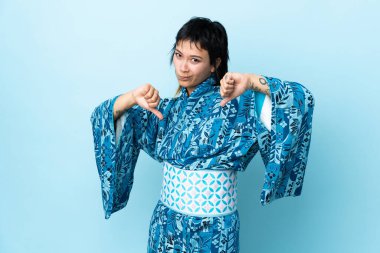 Kimono giyen genç bir kadın mavi arka planda gururlu ve kendini beğenmiş.