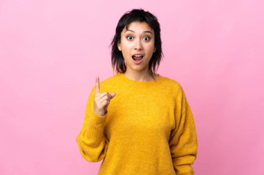 Genç Uruguaylı kadın pembe arka planda tek parmağını kaldırarak çözümü bulmaya çalışıyor.