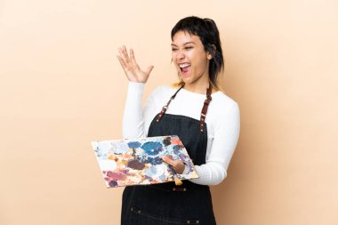 Soyutlanmış arka planda palet tutan genç bir sanatçı mutsuz ve hayal kırıklığına uğramış.