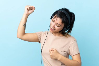 Genç Uruguaylı kız soyutlanmış mavi arka planda müzik ve dans dinliyor