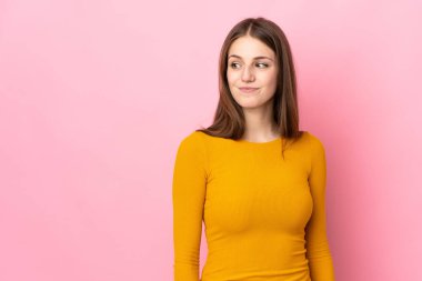 Pembe arka planda izole edilmiş beyaz bir kadın. Taraf ararken şüphe duyuyor.