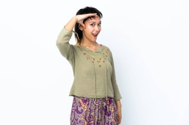 Genç Uruguaylı kız, beyaz arka planda, yan tarafa bakarken sürpriz jest yapıyor.