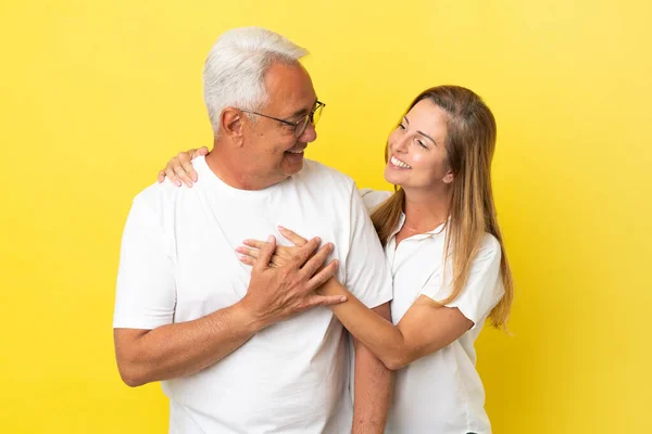 Ζευγάρι Μέσης Ηλικίας Απομονωμένο Κίτρινο Φόντο Γελώντας Και Αγκαλιάζοντας — Φωτογραφία Αρχείου