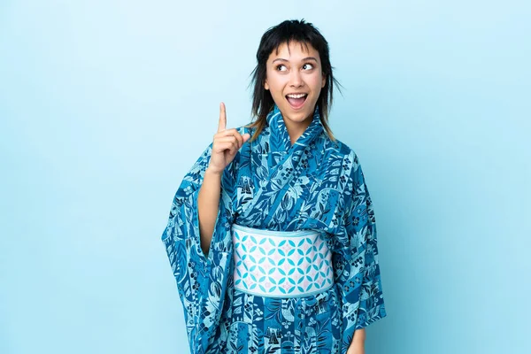 Junge Frau Trägt Kimono Über Isoliertem Blauem Hintergrund Und Denkt — Stockfoto