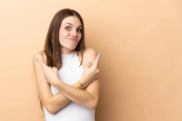 Jonge Kaukasische Vrouw Geïsoleerd Beige Achtergrond Wijzend Naar Lateralen Met — Stockfoto