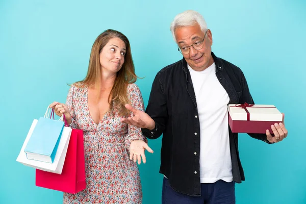 Mavi Arka Planda Alışveriş Çantası Hediye Taşıyan Orta Yaşlı Çift — Stok fotoğraf