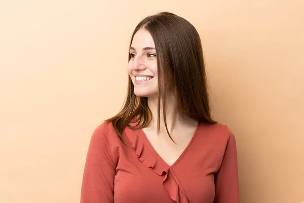 Young Caucasian Woman Isolated Beige Background Looking Side Smiling — Stock Photo, Image