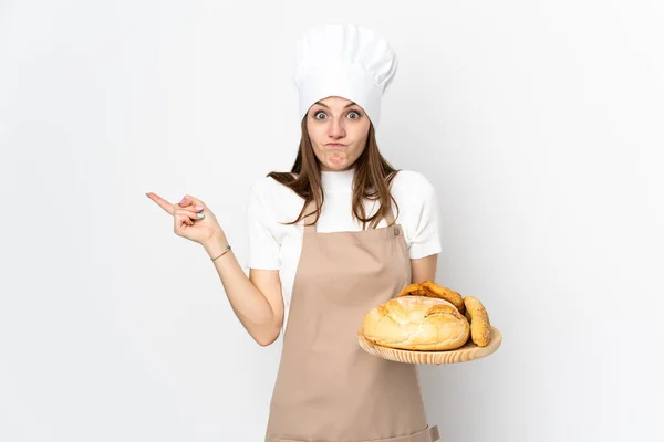 身穿厨师制服的年轻女子被白色背景隔离 指向有疑问的侧面 — 图库照片