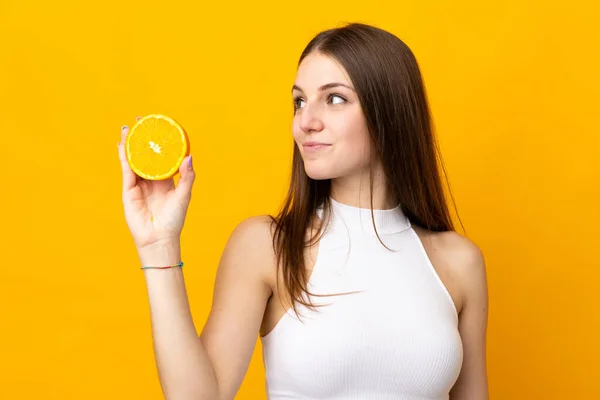 Junge Kaukasische Frau Hält Eine Orange Auf Orangefarbenem Hintergrund — Stockfoto