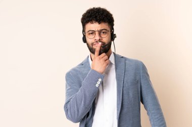 Faslı bir pazarlamacı bej arka planda izole edilmiş bir kulaklıkla çalışıyor.