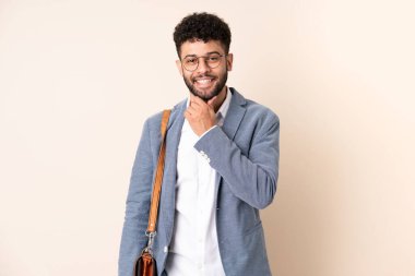 Genç Faslı iş adamı bej arka planda gözlüklü ve gülümseyen bir şekilde izole edilmiş.