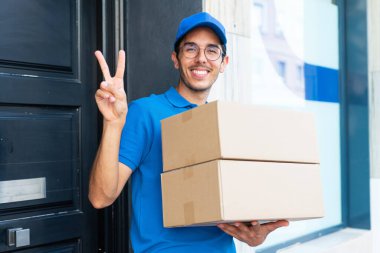 Dışarıda kutuları tutan ve zaferi kutlayan genç teslimatçı.