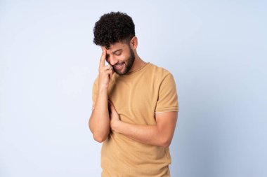 Genç Faslı adam mavi arka planda izole edilmiş gülüyor.